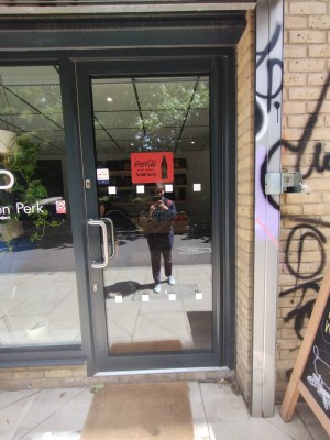 Glass door with black frame ahead. Pull silver metal handle on left to open.