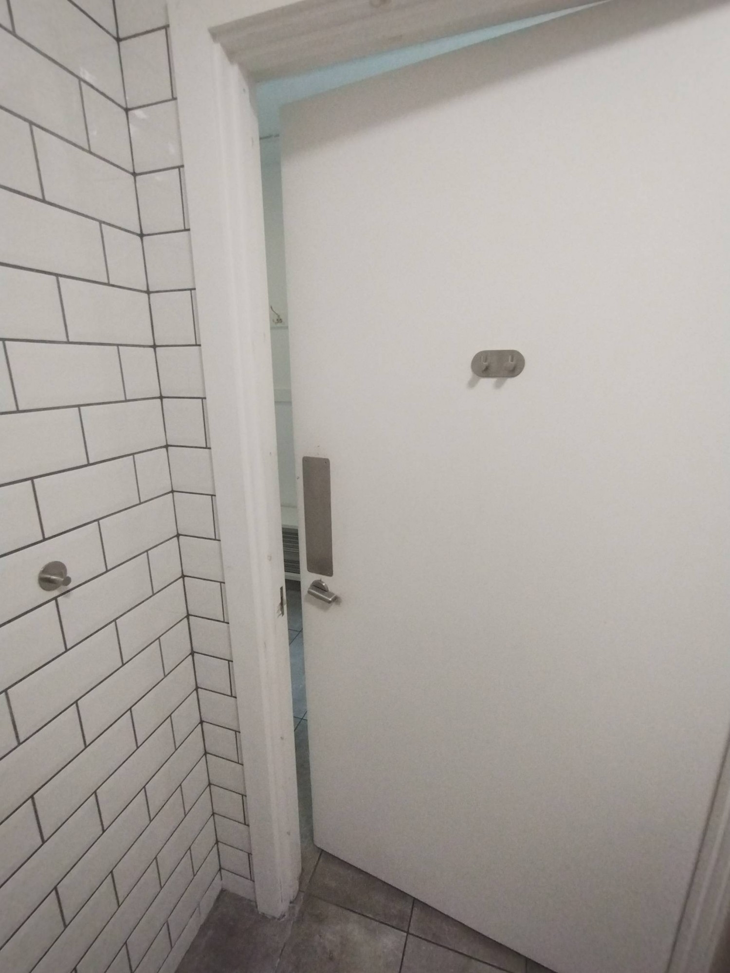 Back end of bathroom door. High hanging hooks on door. Seated-height hanging hook left of door.