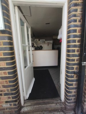 White wooden door with glass panels. Push open to the left. Small step at door.