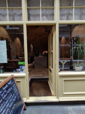 Glass door with yellow frame. Push from left to open.