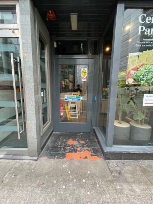 From street facing venue. Wood-panelled glass door ahead. No handle. Door opens outwards from inside.