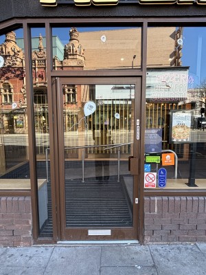 Glass door with brown frame ahead. Pull from right to open.