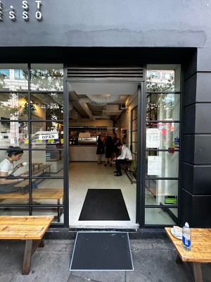 Glass single door with black frames. Silver handle on left. Push to open. Benches to immediate left and right of door.
