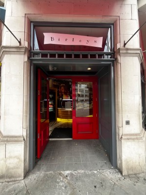 Facing entrance with double red doors and black vertical metal handles. Pull to open.