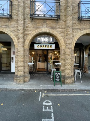 Brick open archway. One step up before archway. A-board sign on right of arch.