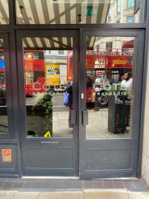 Grey metal-framed glass doors. One step up before door. Pull metal handles at centre to open.