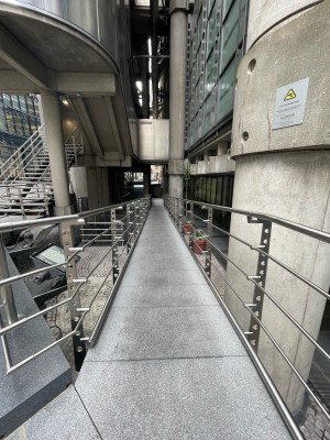 From street facing ramp down. Metal handrails on left and right.