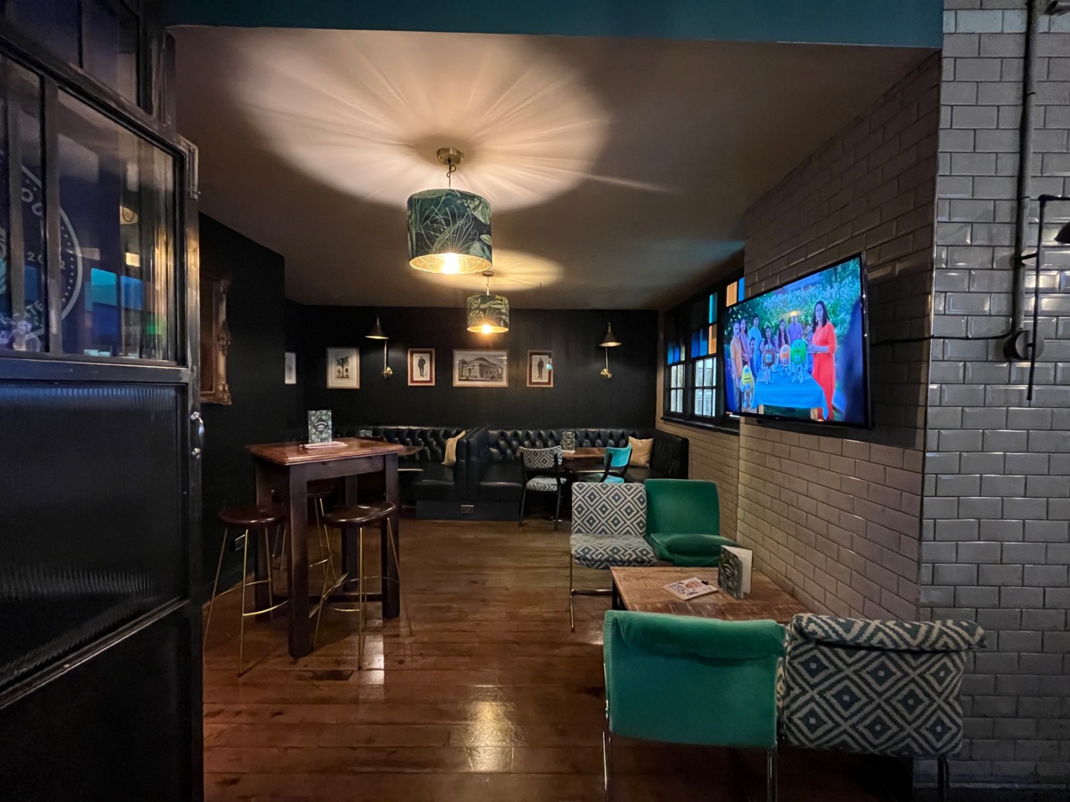 From back of main area looking right. Half booth at the back. Standing height table on the left. Low table and screen on the right.