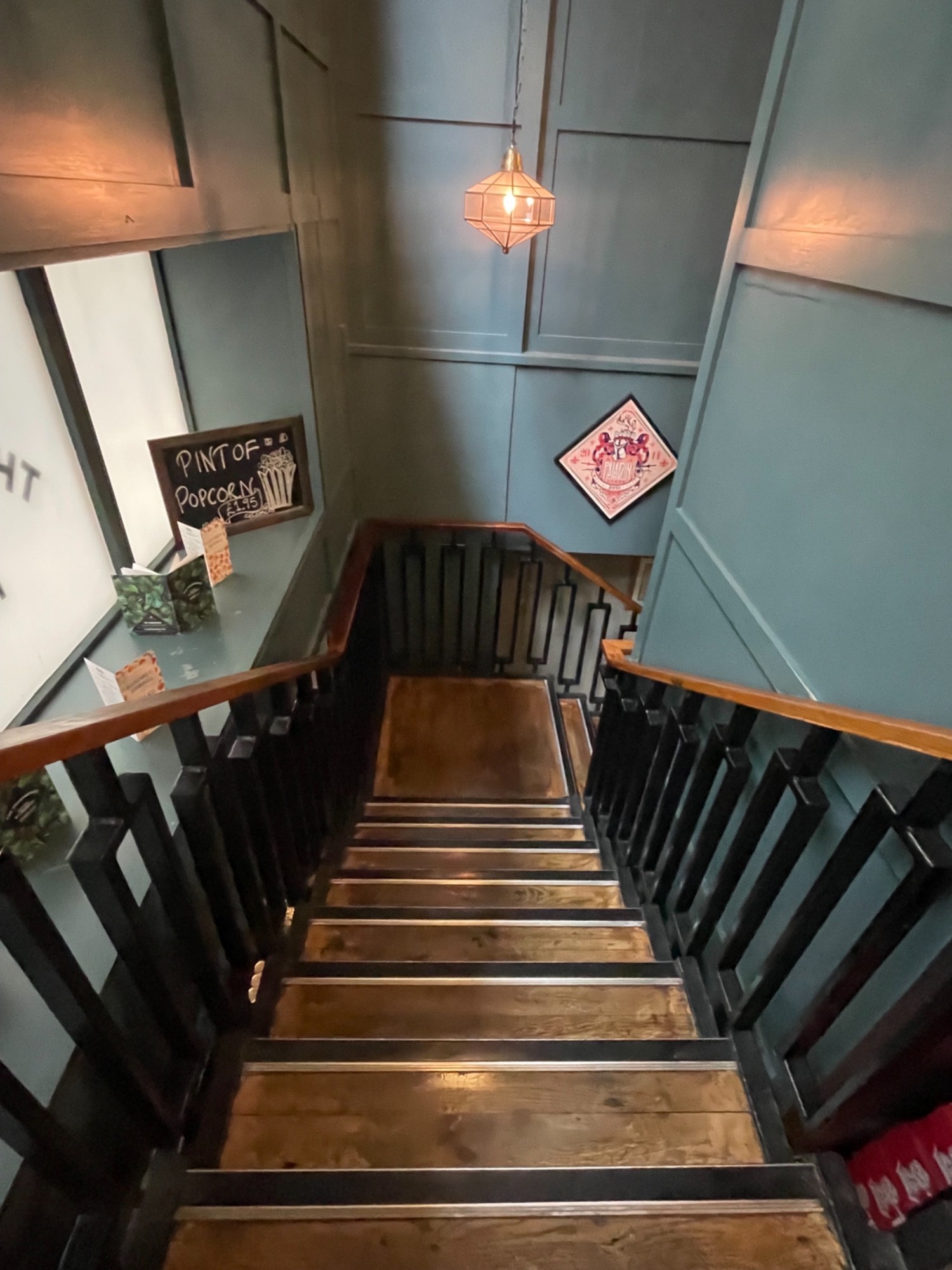From top of the stairs looking down. Hand rail on left and right side. She’s lead to Landing. Colour contrast steps.