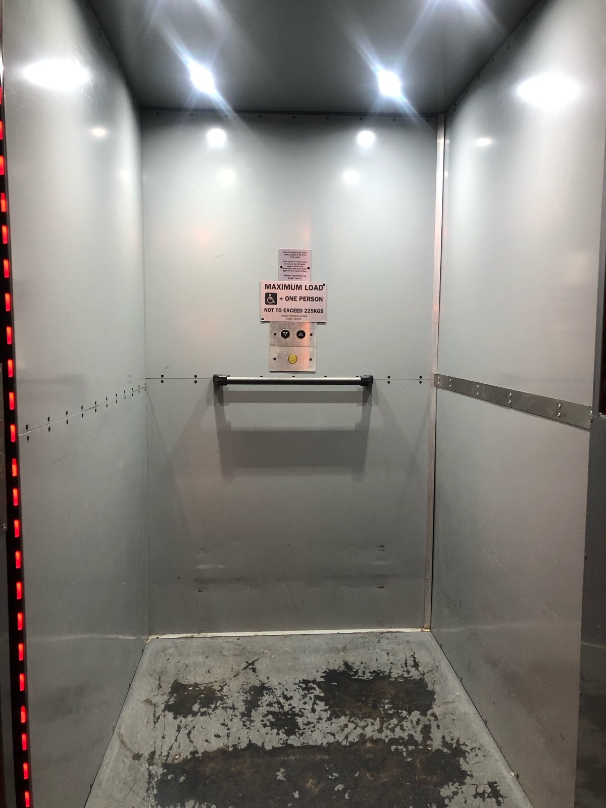 From lift door facing straight. Small grab rail in centre of back wall.