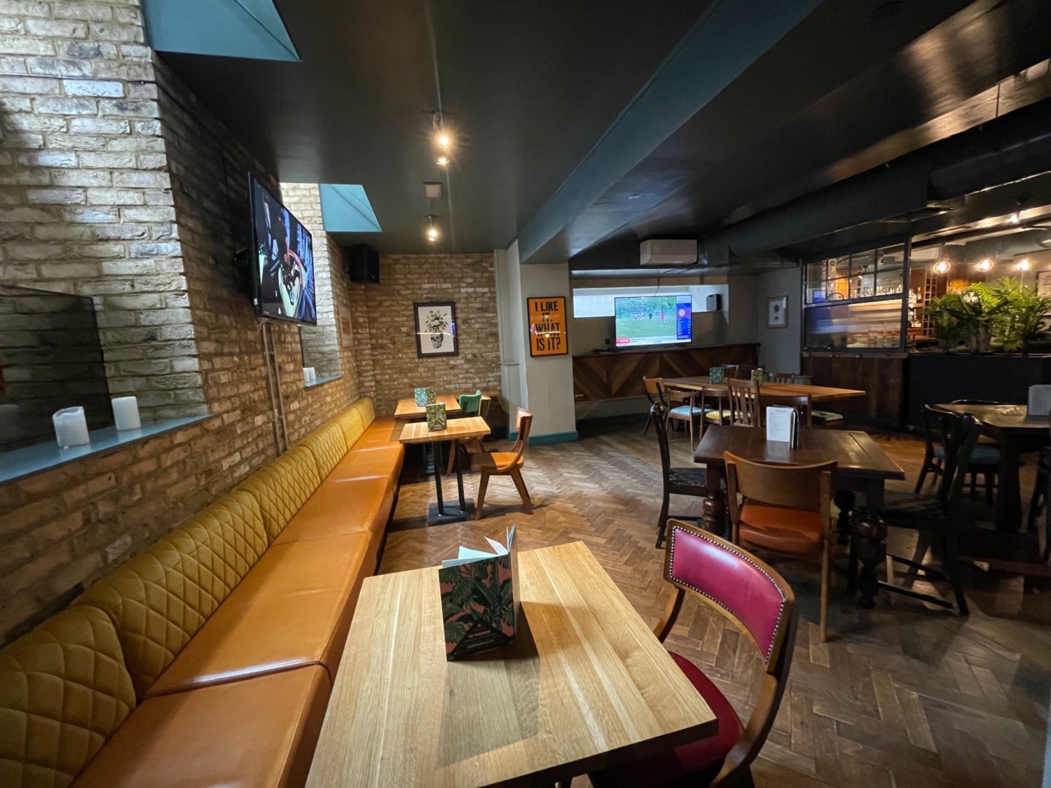 From back of downstairs area looking right. Half booth seating along left side. Tables and chairs in back left corner and centre.