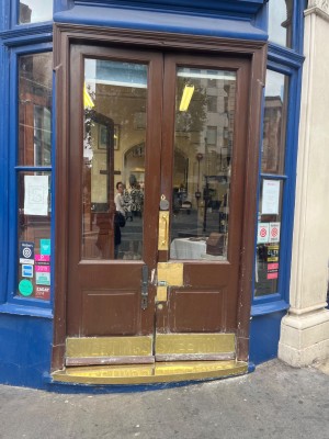 Brown doors in middle of entrance. Gold push handle on the left of the right door.
