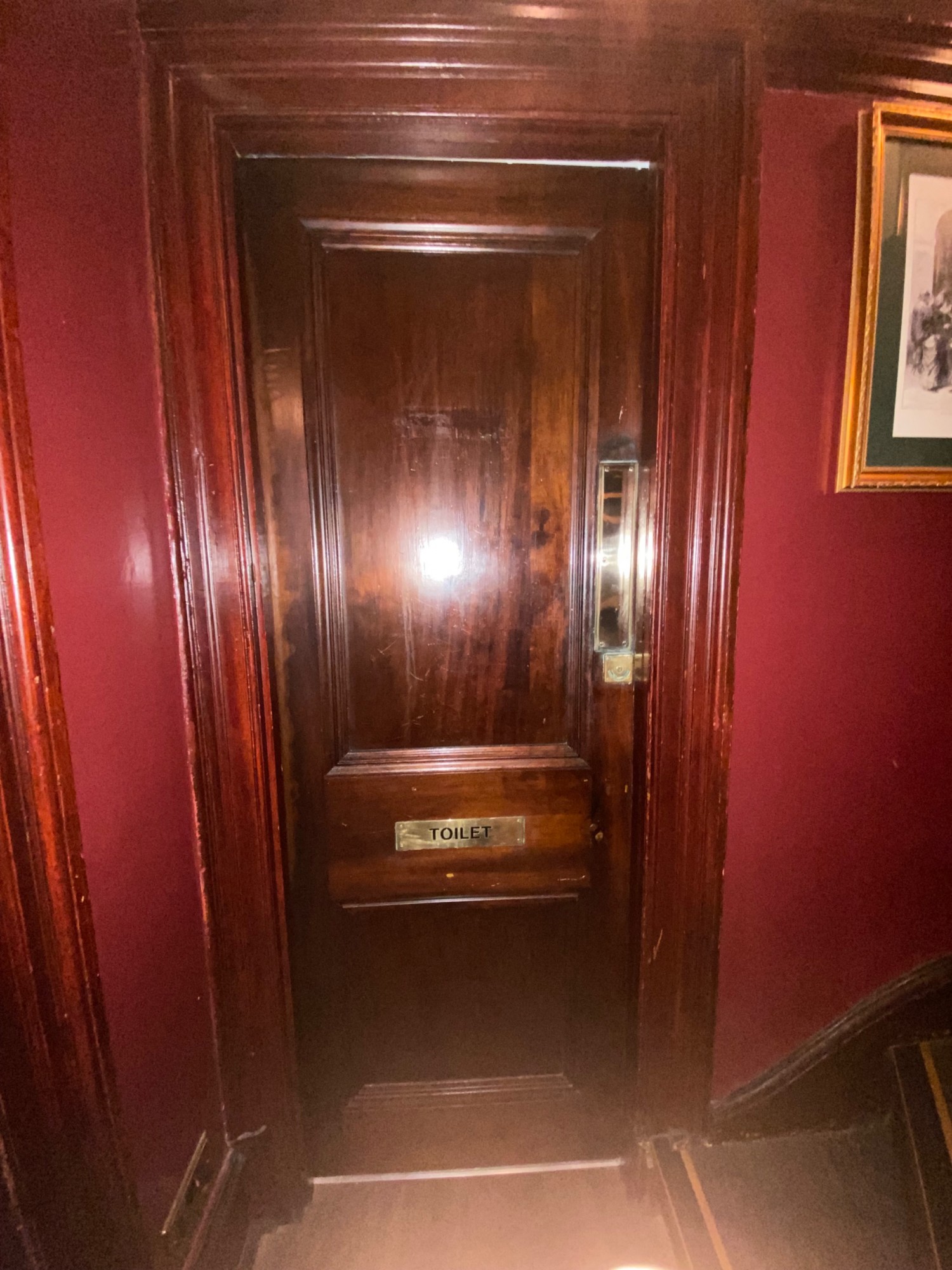 From before door to upstairs seating facing right. Wooden door ahead. Push on right to open.