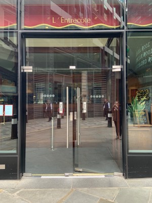 Facing preceding glass doors. Push silver metal handles in centre to open.
