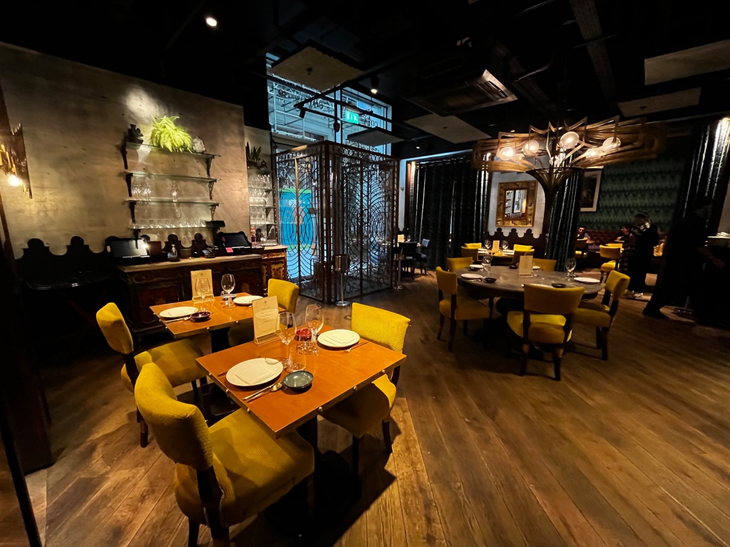Continuation of main area. Tables and chairs throughout space. Area continues ahead through curtains and to right.