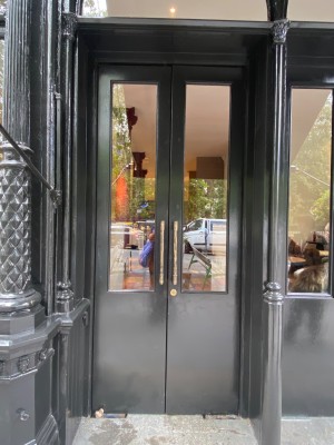 Glass doors with black frame ahead. Pull doors to open via handles in center.
