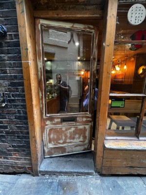 Wooden framed glass door ahead. Push golden handle on right to open.