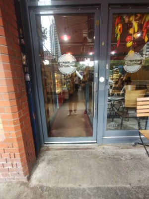 Glass door with grey frames. Pull metal frame on right to open. Built in ramp before door.