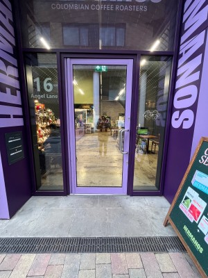 Glass door with purple metal frame. Push from right to open.
