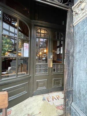 From sidewalk facing venue. Glass double doors with green frame. Push to open in center.
