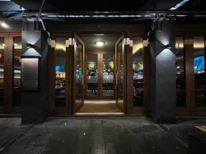 Preceding door. Glass doors with brown frames. Push brass handles in centre to open.