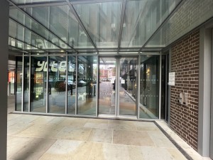 Grey framed automatic sliding doors. Small bump along doors.