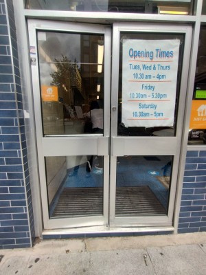 Glass door with silver, metal frame. Push silver handles in middle to open.