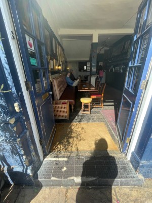 Blue wooden double doors with glass panel. Push metal panel in middle of right door to open.