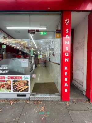 From sidewalk facing straight. Main entrance ahead. Glass door with metal push to open handle on left.