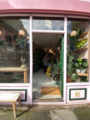 Facing pink framed green glass door. Push from left to open.