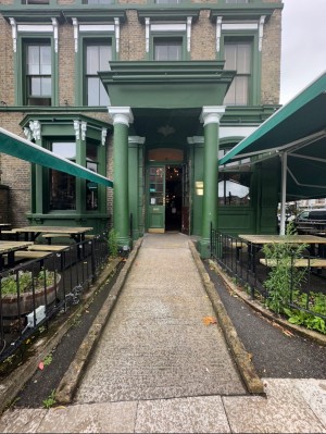 Main entrance with built in ramp followed by double wood and glass door.