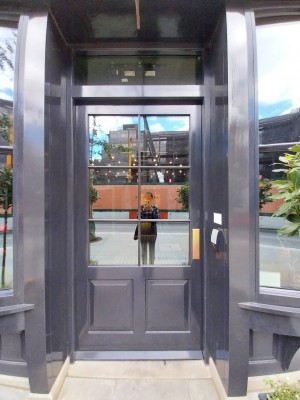 Black door with glass panels ahead. Push door to open from the right.