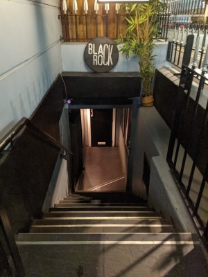 Stairs leading to main entrance. Black handrail along left. Last step turns towards left.