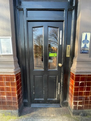 Black wood-panelled glass door ahead. Push from brass handle on right to open.