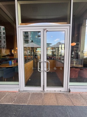Double glass doors with metal frame ahead. Push metal handles at center to open.