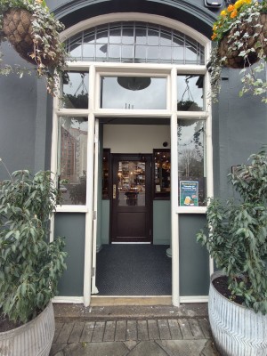 Facing white doorframed green glass door. Push from right to open.