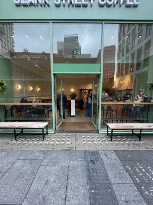 Green metal-framed glass doors ahead. Push black metal vertical handles at centre to open.