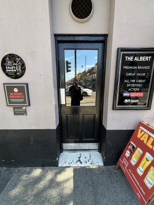 Glass door with black frame ahead. Push from left to open.