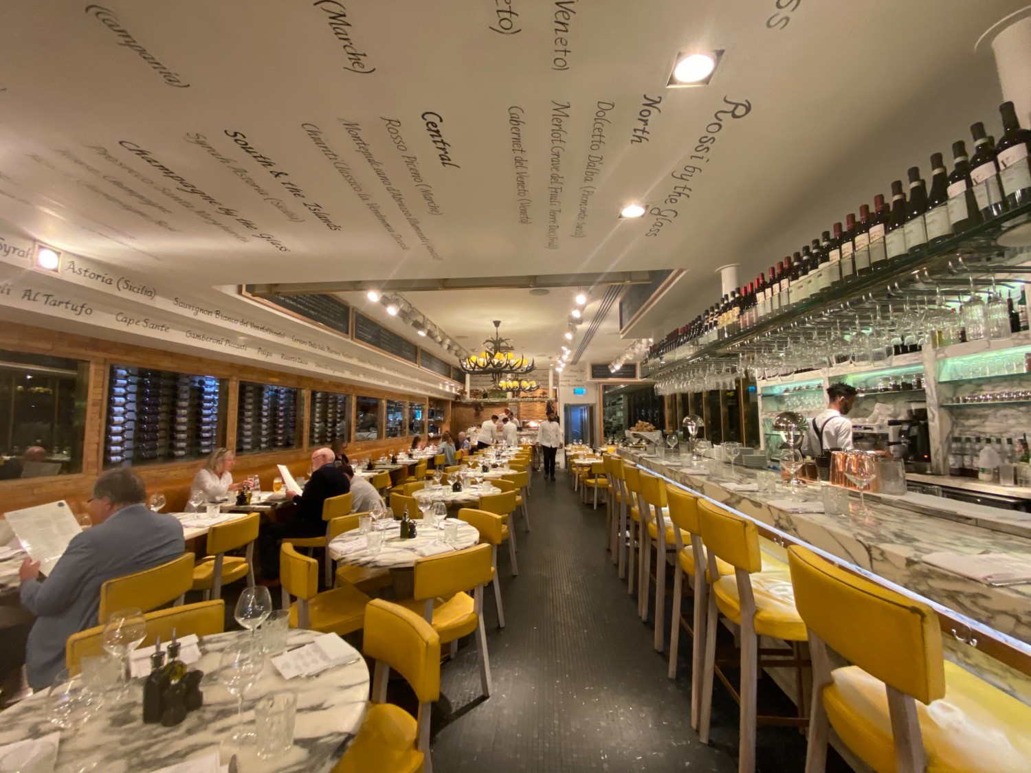Looking straight from middle of the main area. Tables and chairs and half benches on the left. Bar with stools on the right.