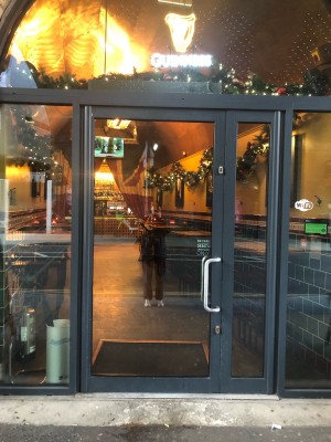 Glass door with grey frame. Push metal handle on right to open.