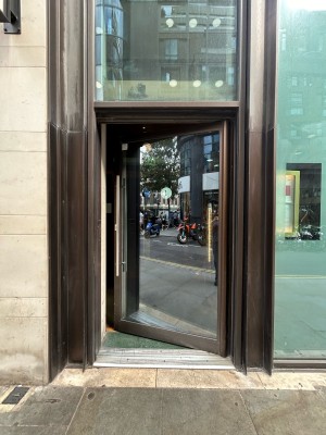 Single glass door with vertical silver handle on left. Push to open.