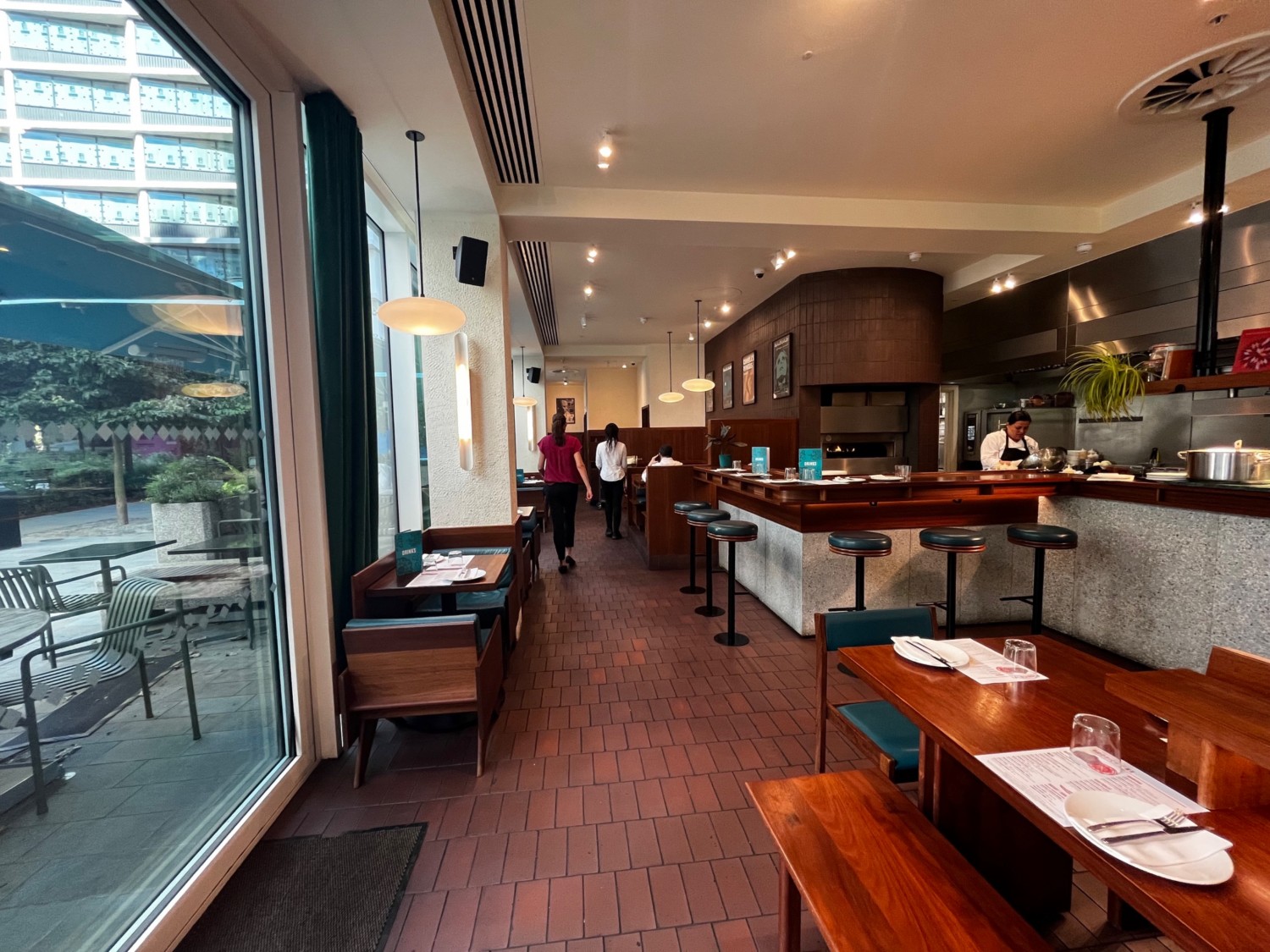 Continuation of main area seating second bar counter with backless stools on right. Table with chairs on left. Area continues ahead.