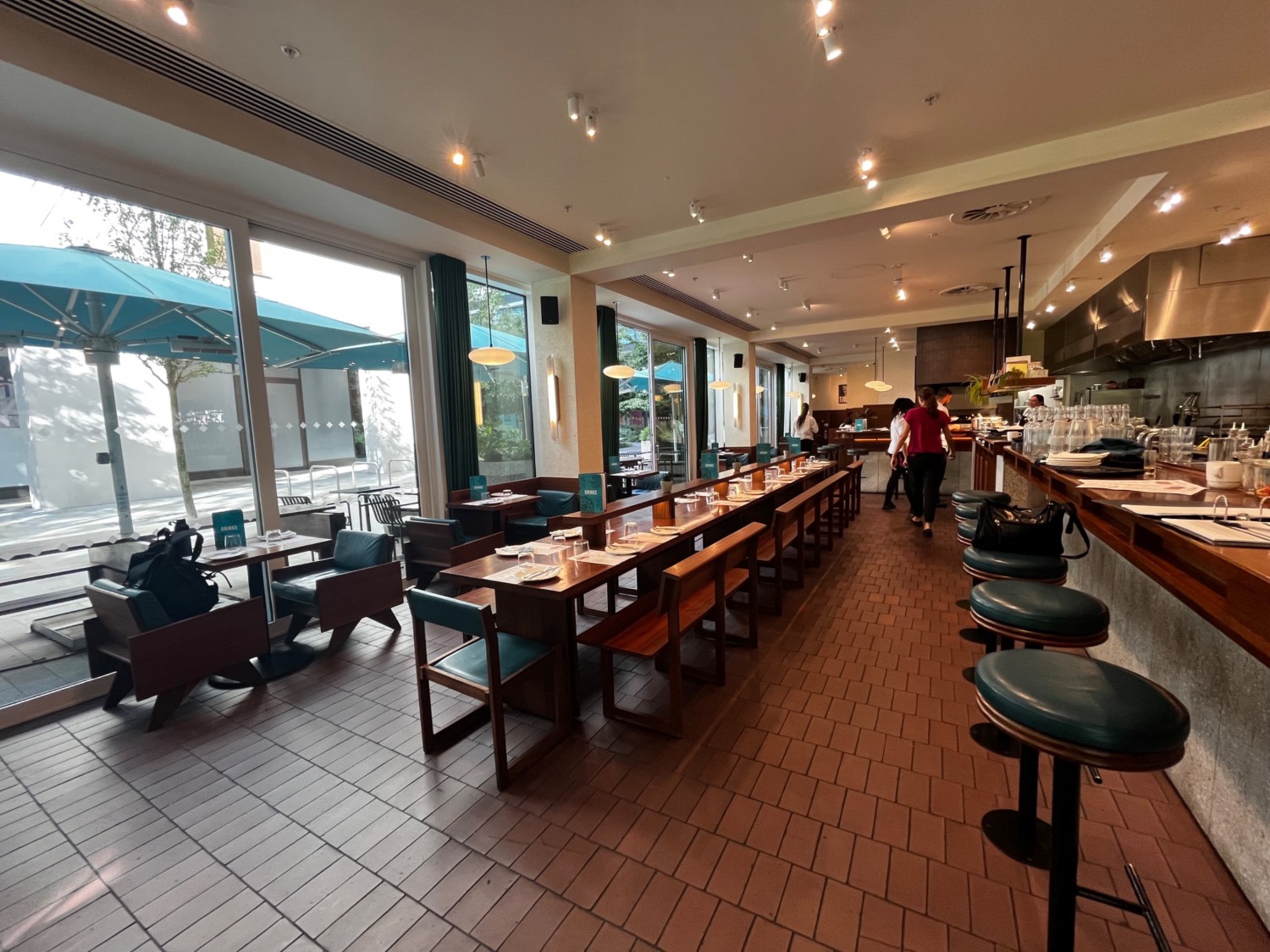 Right side main area seating. Bar counter with backless stools on right, tables with chairs on left and with benches in middle. Area continues ahead.