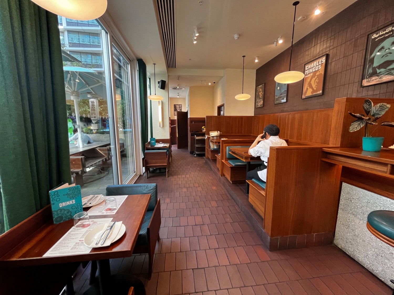 Continuation of main area past second bar counter. Booths on right wall. Path to accessible bathroom ahead past table with chairs on left wall.