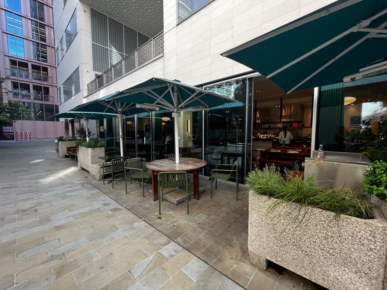 Continuation of outdoor area on left side of venue. Table with chairs and half booth on outer wall. Area continues along outer wall.