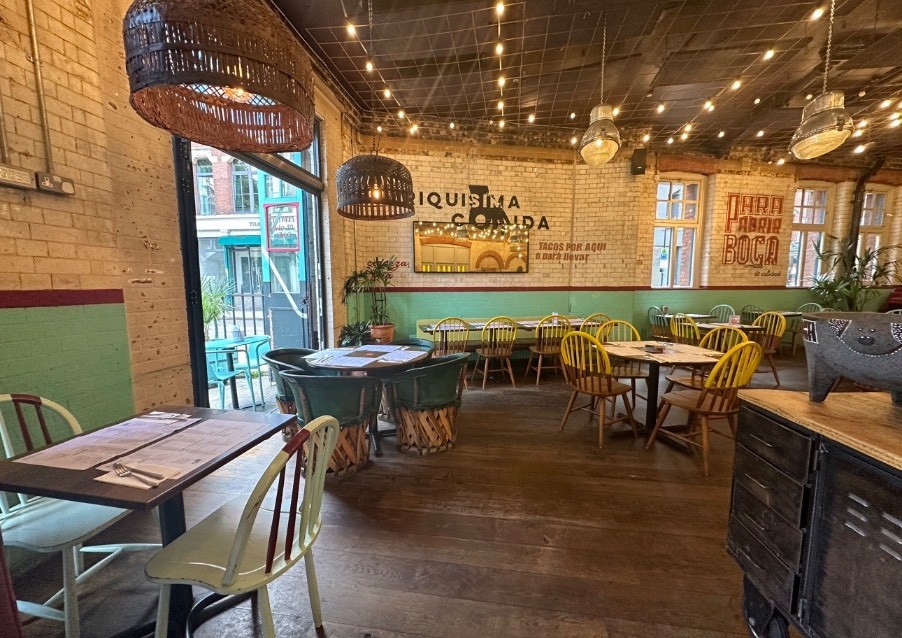 From after welcome desk, looking left. Tables and chairs on left and ahead. Display table on right.