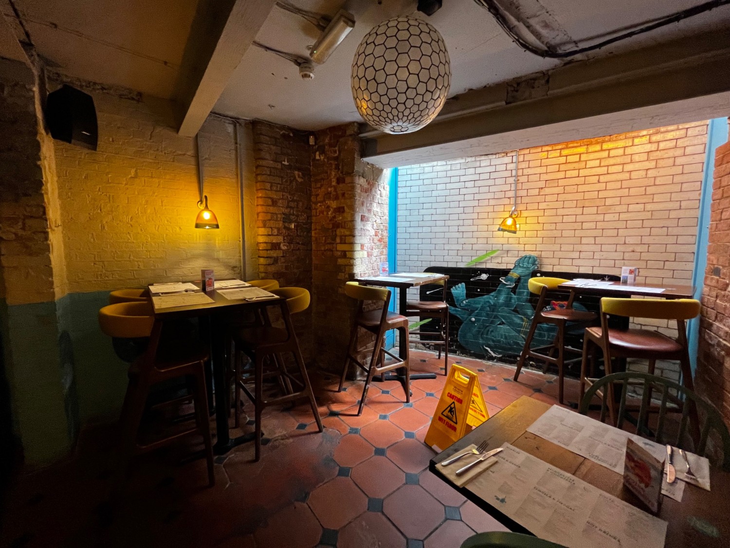 Continuation of downstairs area to right. High tables with back supported stools in back right corner.