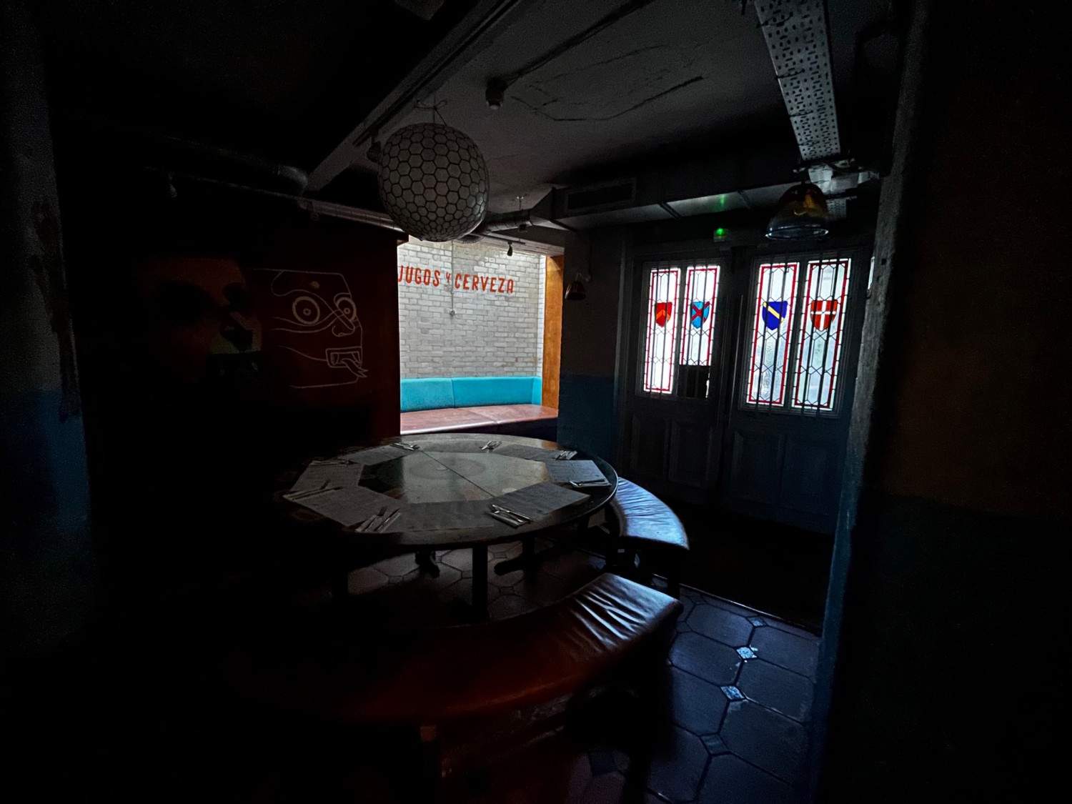 Continuation of downstairs area to left. Round table with benches. Couch behind table through doorway.