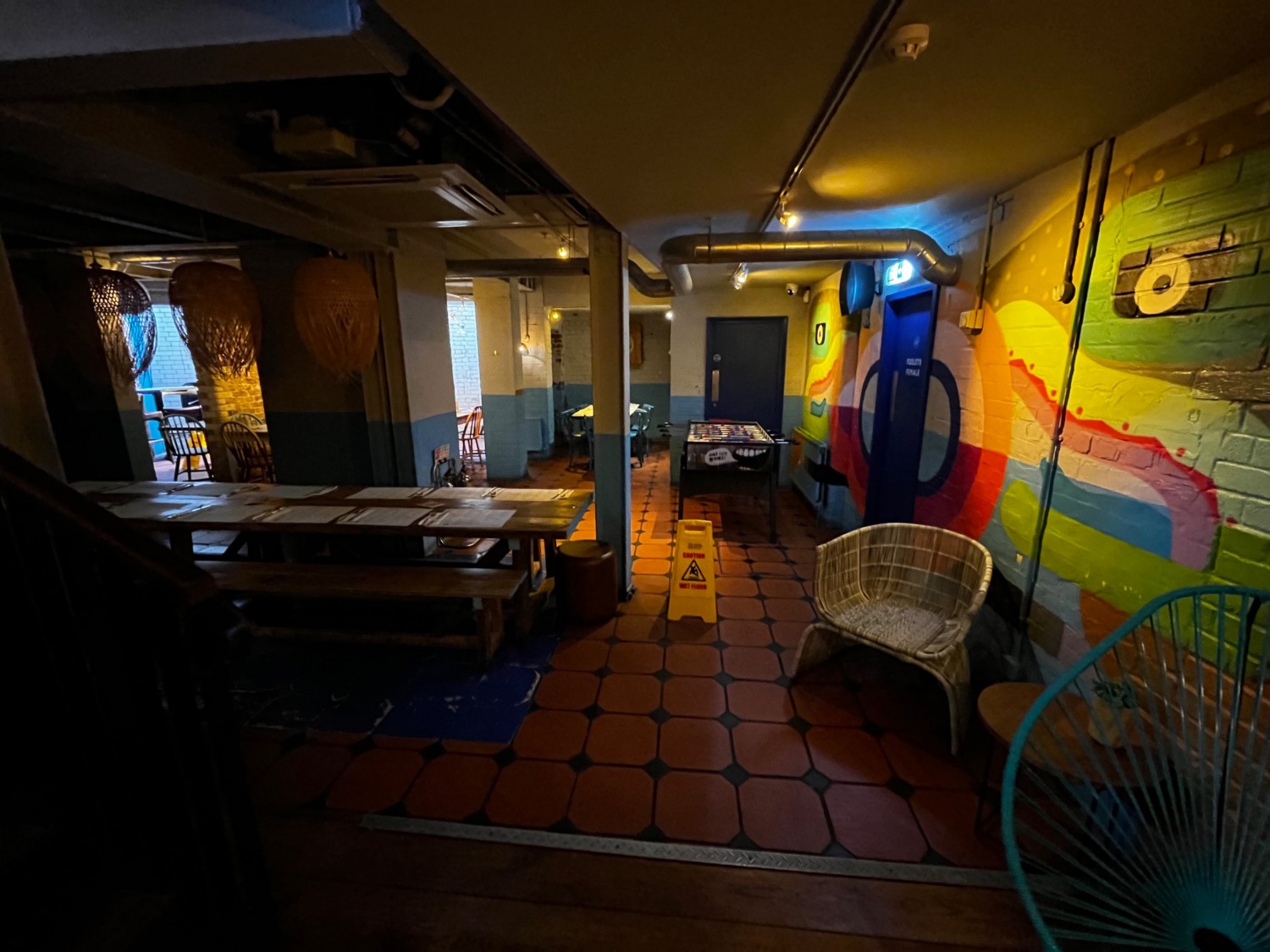 Downstairs seating area facing left from foot of stairs. Low table on right. Area continues ahead and to left.