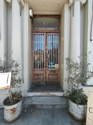 Two steps up to wooden framed glass doors. Push golden handles in centre to open.